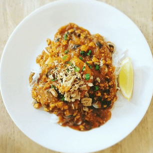 Vegan Filipino palabok with lemon wedge on a round plate.