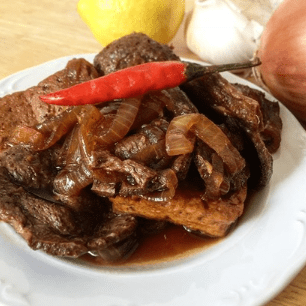 Vegan Filipino bistek with a red chili pepper on top.